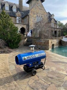 Hugg & Hall-stickered generator outside a large brick house with a pool. 